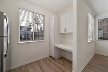 Kitchen with a refrigerator, wooden floors, and white cabinets.